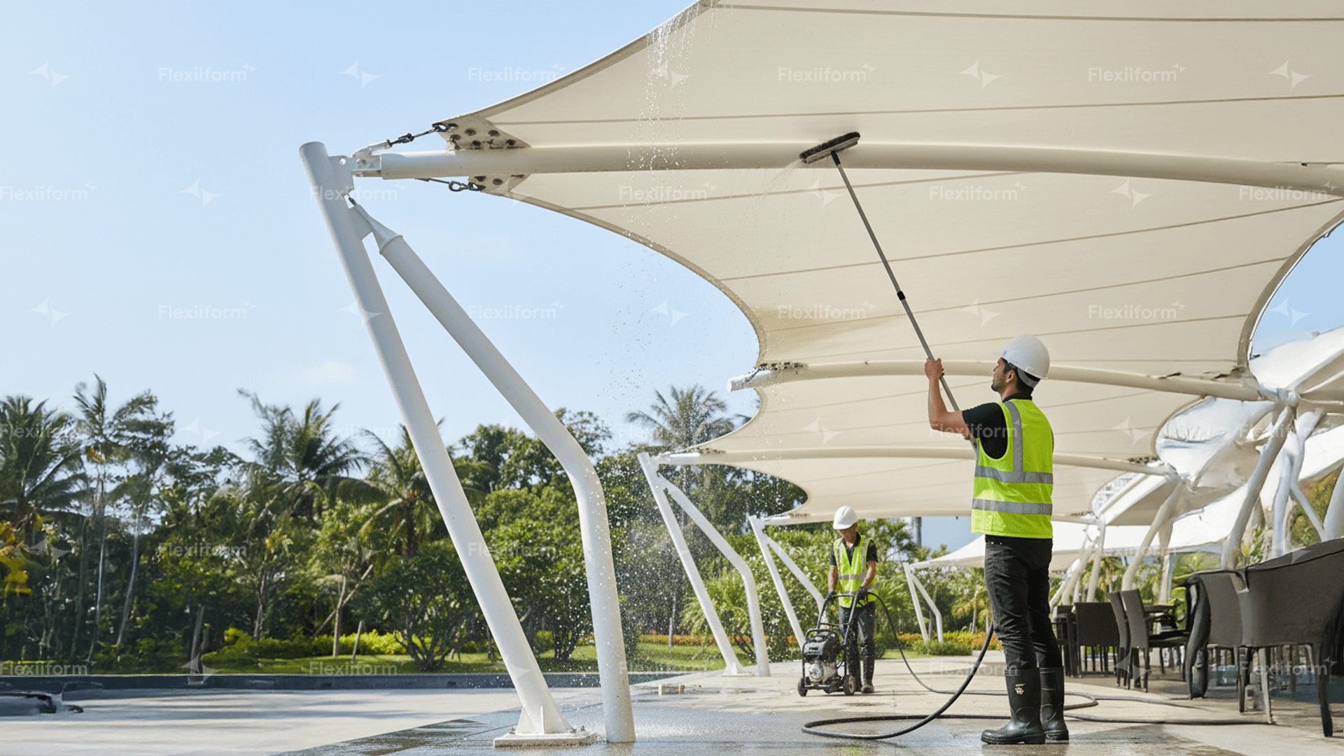 Công nhân đội mũ trắng cầm chổi cán dài xịt rửa mái màng căng