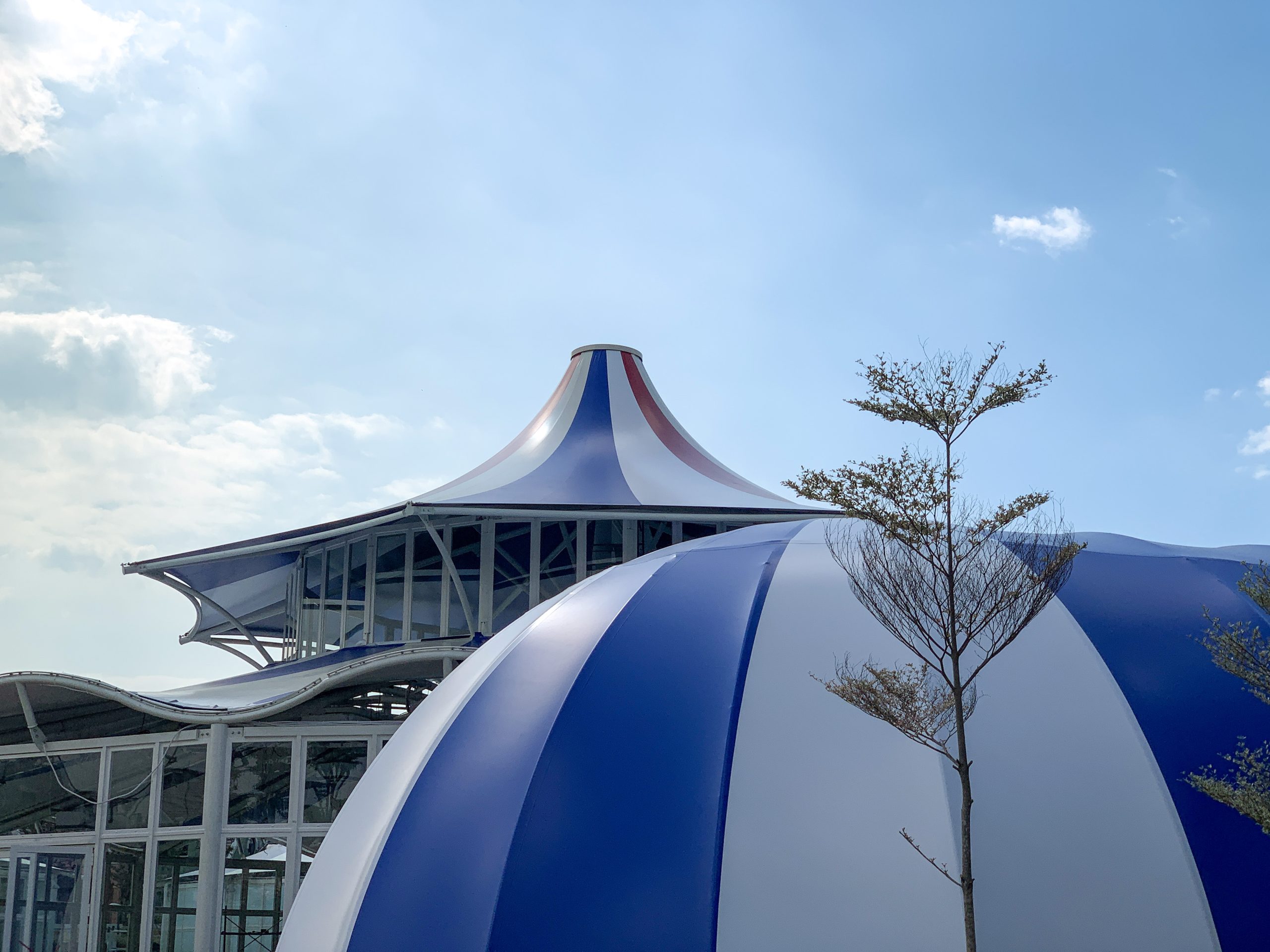 Capsule Dome sọc xanh dương trắng tại Ecopark Long An, phía sau là mái che bạt căng dạng chóp của khu đô thị